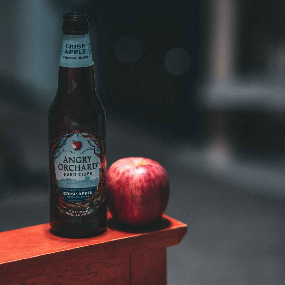angry orchard hard cider bottle beside red apple fruit